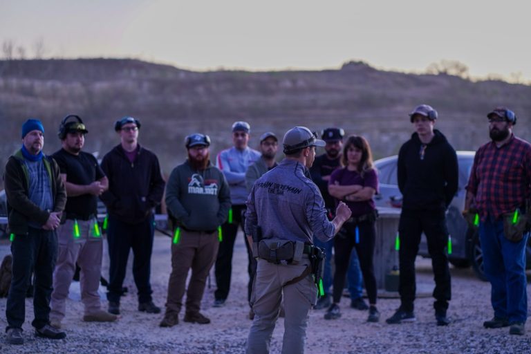 An instructor debriefing Combat Club members at dusk on the outdoor range